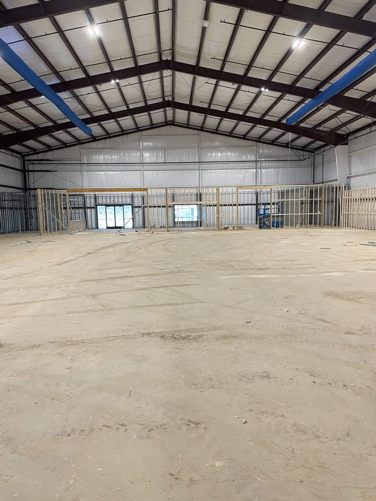 Arena interior during build-out — painted steel frame, insulated roof deck, LED high-bay lighting and framed-out rooms